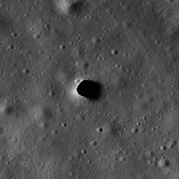 La expansión del foso de Marius Hills muestra un pequeño cráter en el extremo noroeste y pequeñas piedras en el lado sur del agujero.  El agujero tiene unos 65 metros de diámetro.